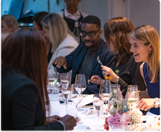 A group of people sat around a dinner table engaged in conversation